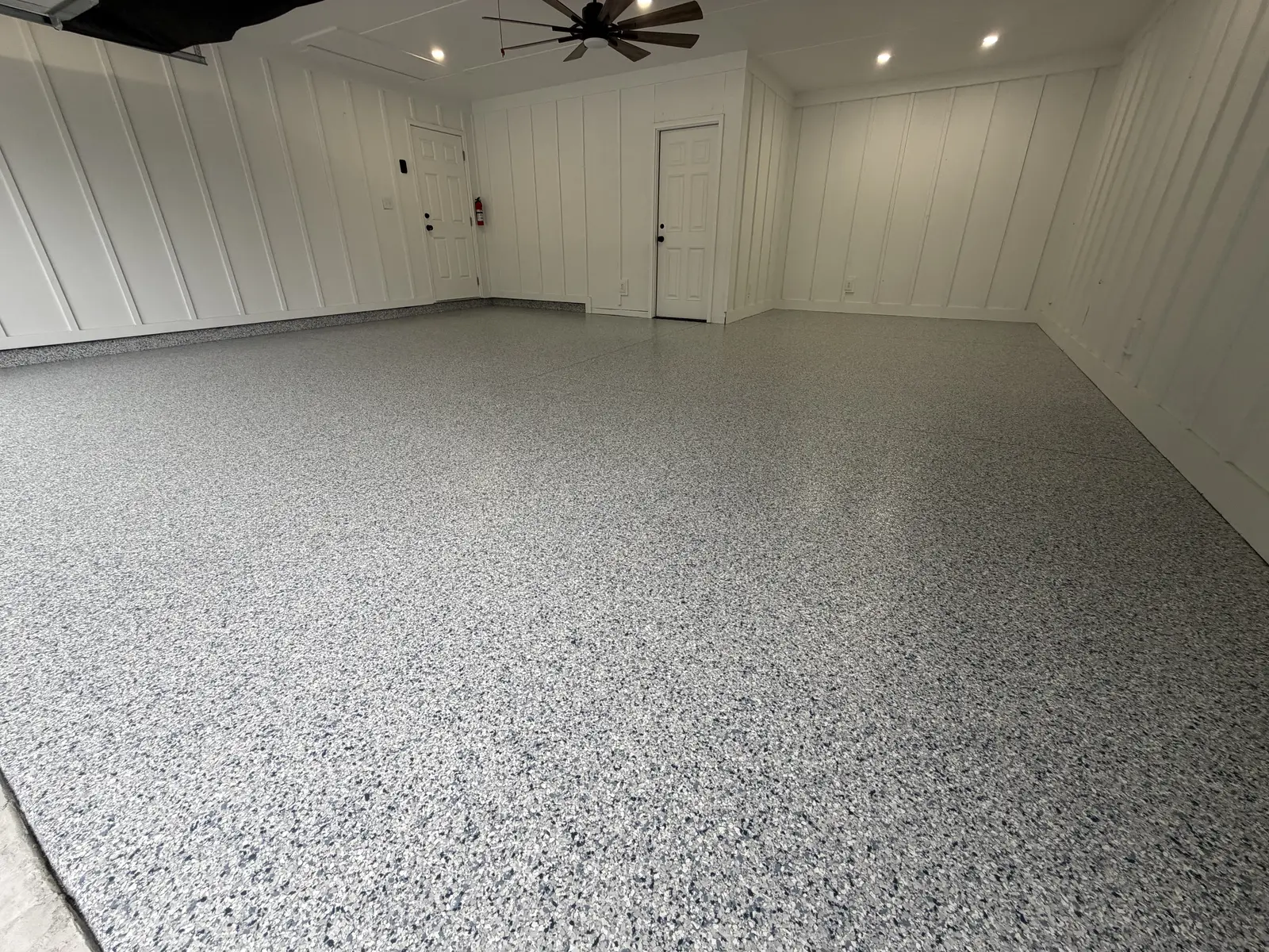 Flake garage floor coating in a garage with white shiplap walls