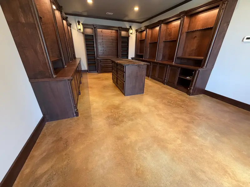 Amber stained concrete floor in a room with dark wood cabinetry