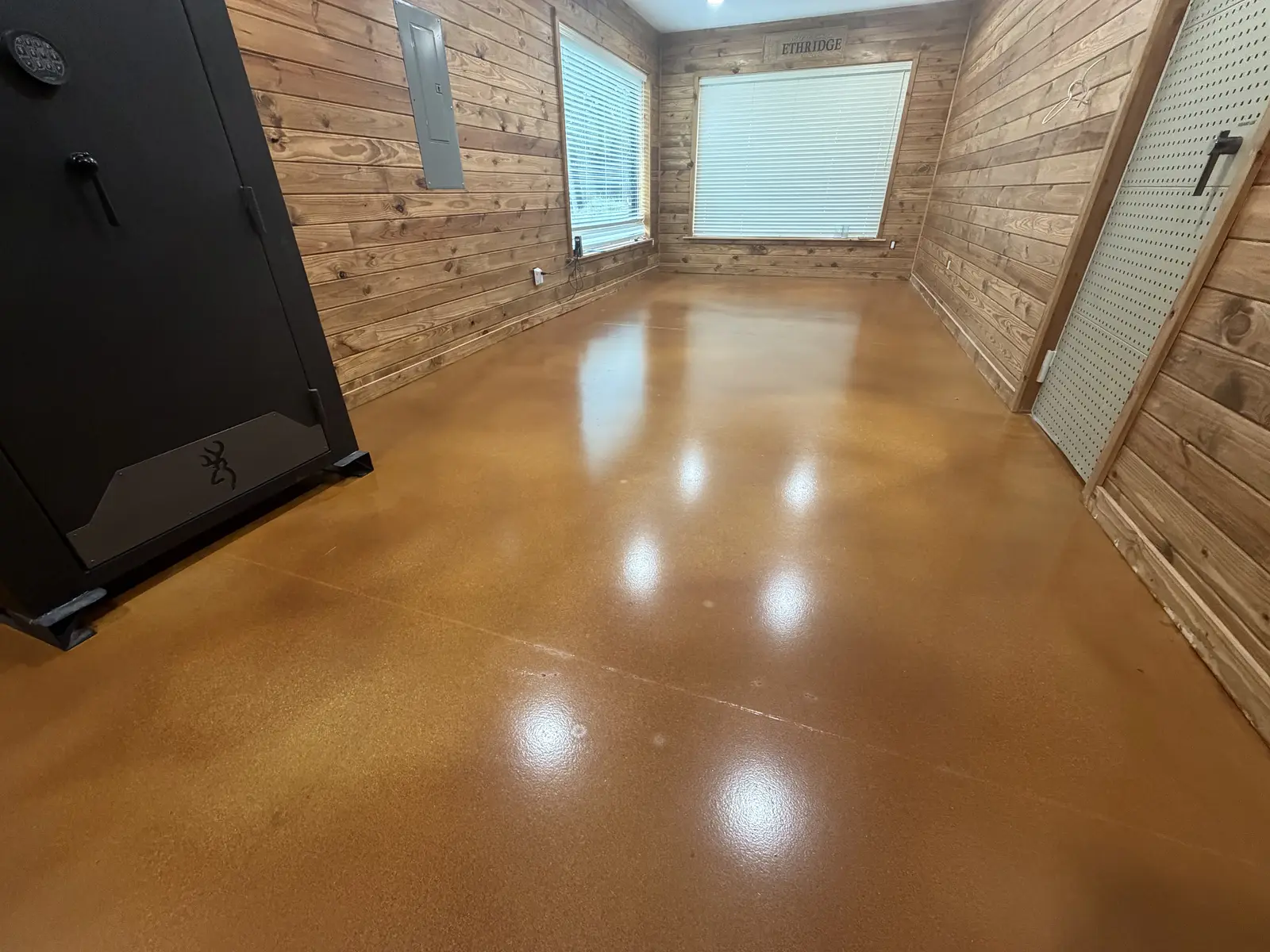 Glossy amber stained concrete floor in a wood-walled room